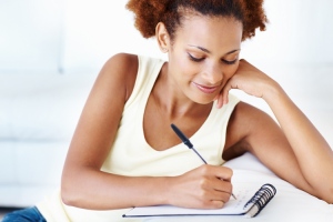 Closeup of smiling African American woman writing on notepad at home