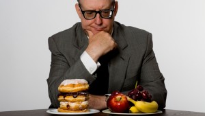 Man contemplating eating healthy or unhealthy food, studio shot